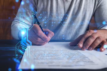 A closeup image of a person holding a pen and preparing to sign a document